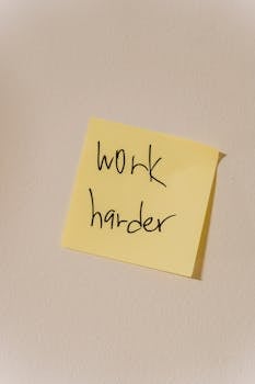 A yellow sticky note with the message 'work harder' inspires productivity in a workspace.