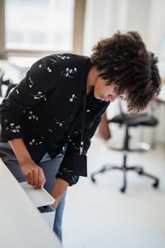 African American woman organizing files at an office desk, epitomizing workplace productivity and focus.