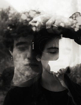 Artistic double exposure portrait blending two individuals' faces in black and white