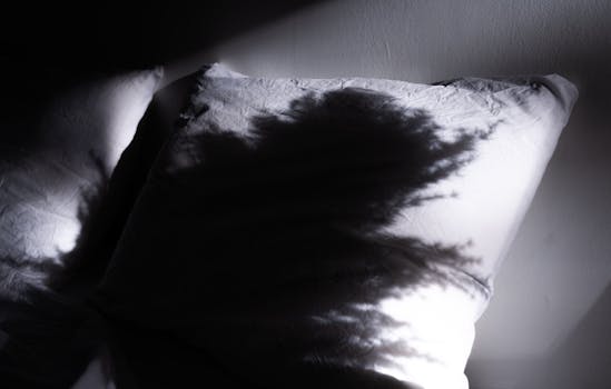 Black and white shadow cast on a wrinkled pillow creating a dramatic scene.