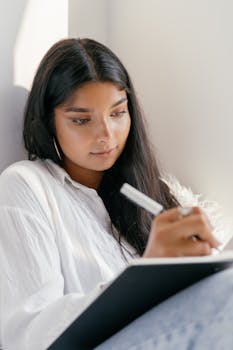 Focused young woman writing in a notebook by natural daylight. Perfect for themes of concentration and creativity.
