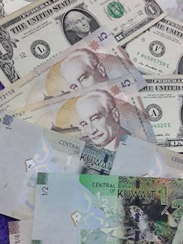 Pile of US dollar and Kuwaiti Dinar banknotes, symbolizing international finance and exchange.