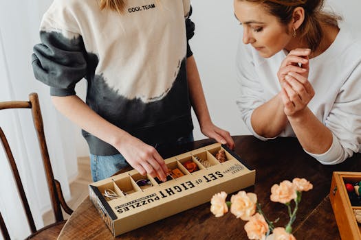 Two women enjoy a puzzle-solving activity with a boxed puzzle set indoors.