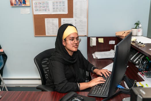 Young businesswoman in hijab working diligently at her desk in a professional office setting.