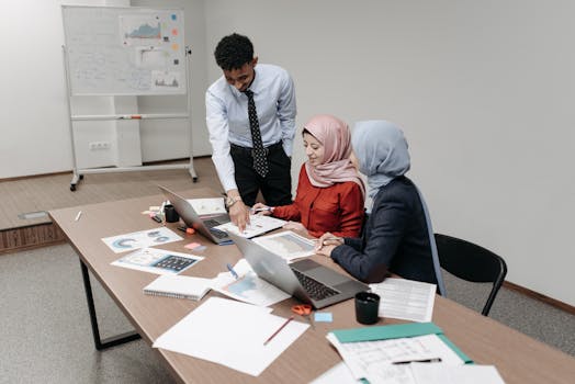 Young professionals collaborating around a desk in an office setting, focused on teamwork and planning.
