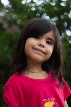 Portrait of a smiling girl with black hair in a vibrant pink shirt outdoors in Breves, Brazil.